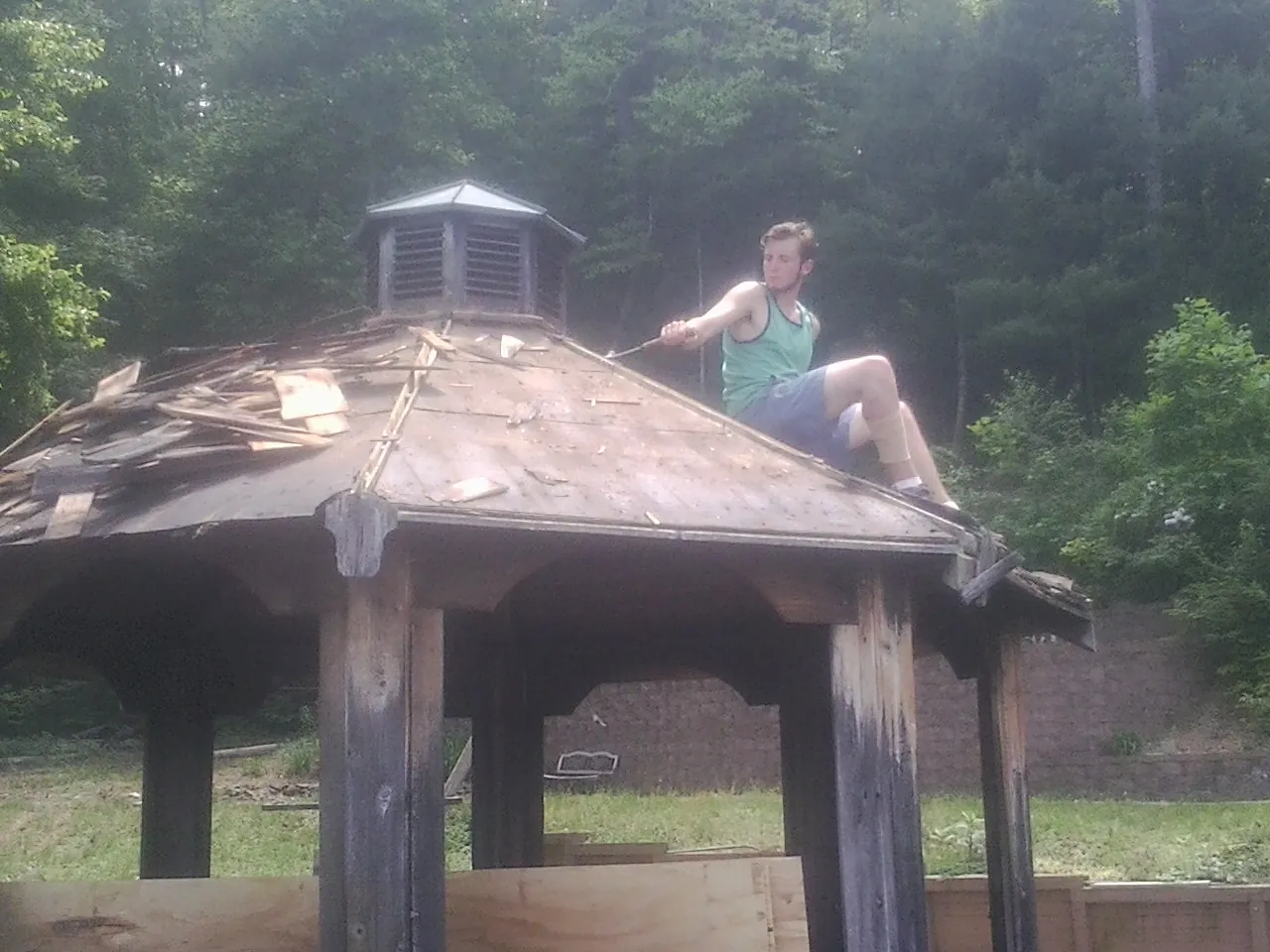 Tearing the old roof off a wooden gazebo before new shakes in Lake Peekskill