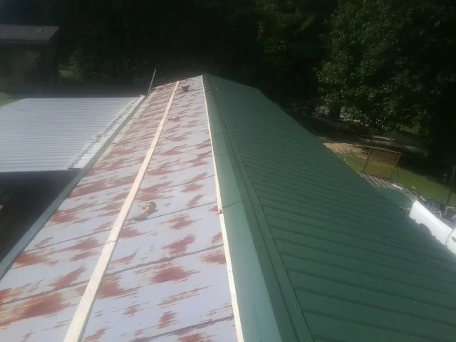 Old rusted panels beside newly installed green metal roofing — Wind Damage Roof Repair by Roofing Brothers in Lake Peekskill