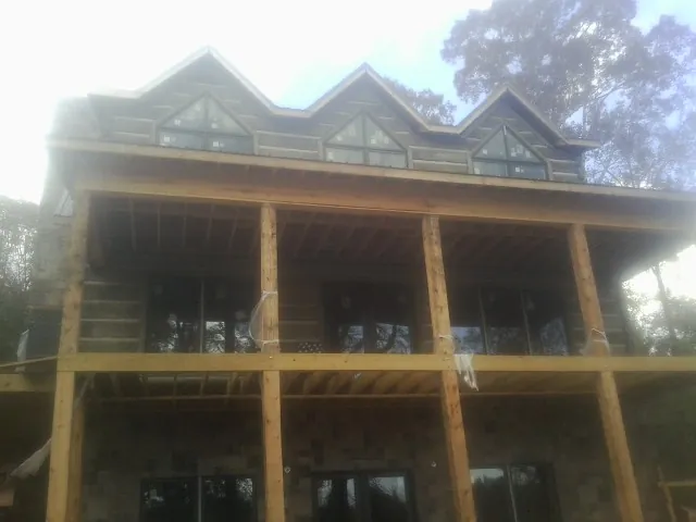 Dormers and porch framing on a large log home under construction — Roof Coating work by our crew in Lake Peekskill