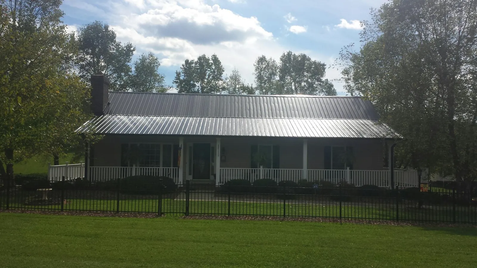 Gray metal roof on a brick ranch with a full width front porch — Gutter Guard Installation work by our crew in Lake Peekskill