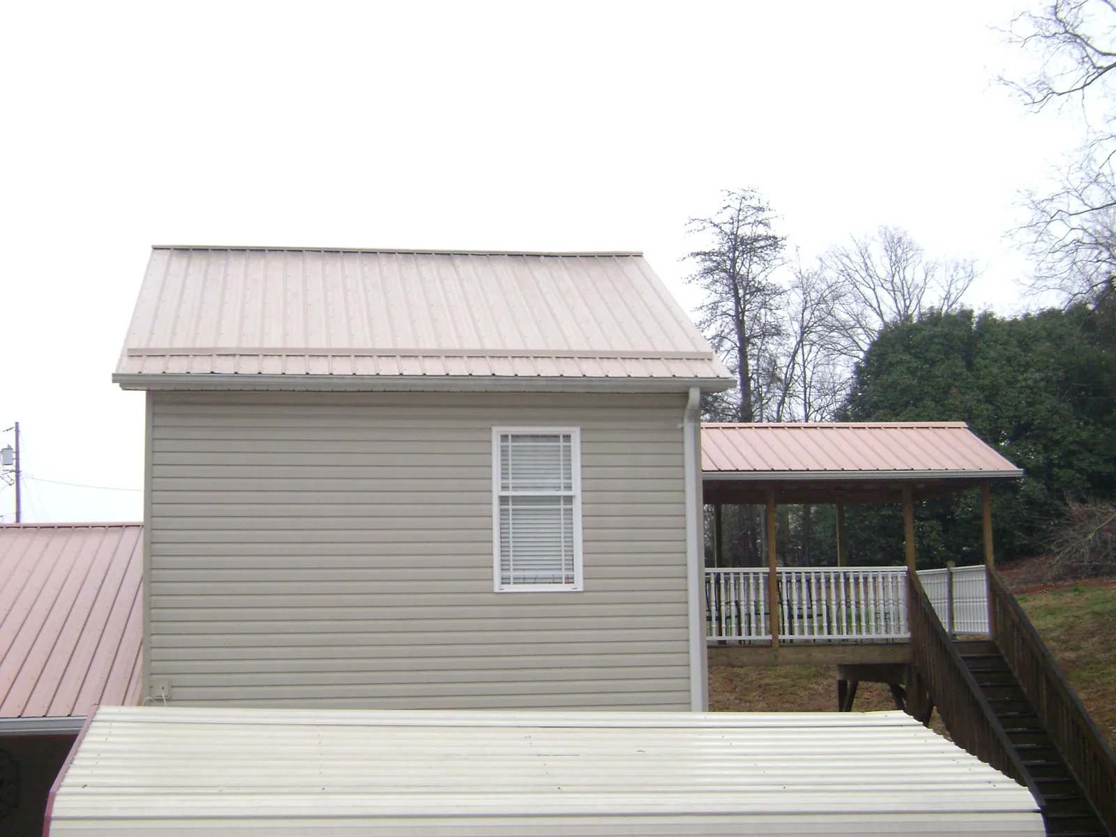 Tan metal roofs on a two story addition and attached porch, from a Roof Replacement job in Lake Peekskill