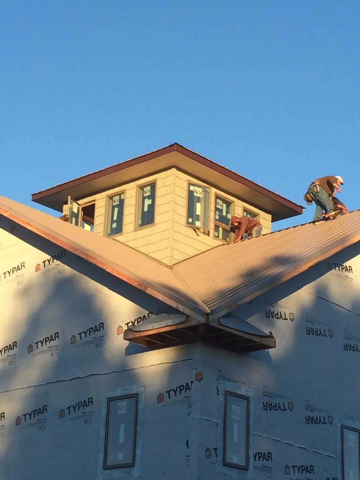 Roofers working around a rooftop cupola on a new metal roof at sunset — Roof Waterproofing in Lake Peekskill by Roofing Brothers